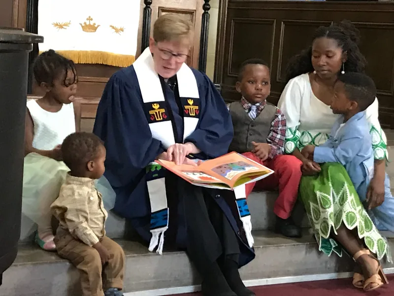 The pastor sharing the Children's Message with children gathered at the front of the sanctuary during worship