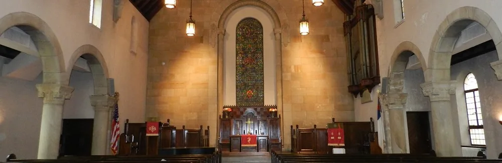 Inside the sanctuary at Sixth Presbyterian Church, looking toward the chancel, stained glass window and stone arcade